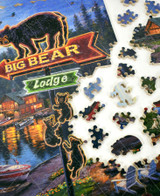  Piece taken apart of Big Bear Lodge wooden jigsaw puzzle introducing families vacationing on a lake in cabins that line the perimeter of the shore. A LED sign of an arrow with a bear and her cubs reads, "Big Bear Lodge." Lights from the cabins and a campfire glow against the dark pine trees in the background. 