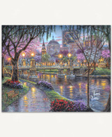 Lagoon Bridge wooden jigsaw puzzle showcases an evening scene in the park along the bay. Trees and flowers bloom as petals fall on a pathway leading to a bridge. Across the bridge is a statue of a man on horseback with city buildings in the background. 
