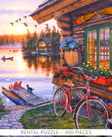  Close-up of Away From It All wooden jigsaw puzzle featuring a log cabin on the lake, with its door half open and a fire blazing inside. There is a path that leads to a boat dock, where a dog stands looking out towards the water as its owner takes a canoe out for a ride as the sun sets. A flock of geese fly overhead and another cabin's lights glow in between the pine trees. 