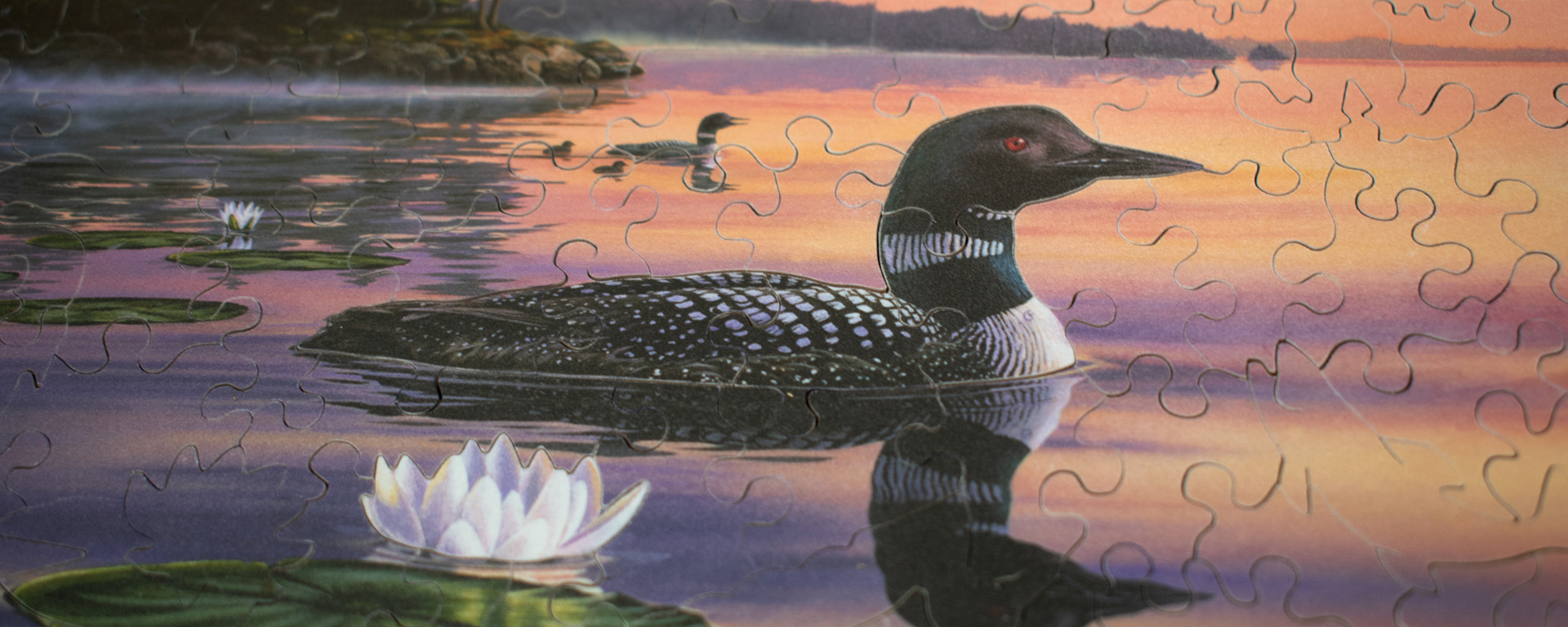 Wooden waterfowl puzzle featuring loons and water lillies on a misty lake.
