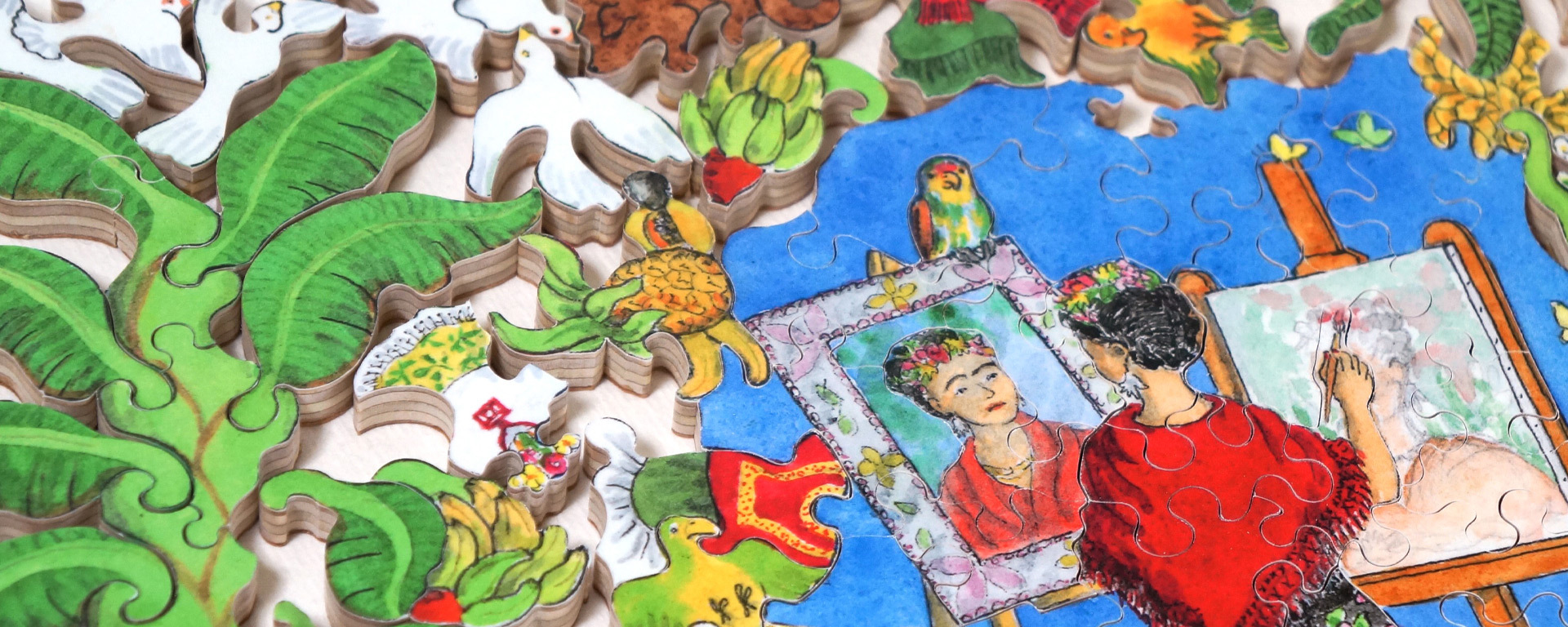 Wooden famous art puzzle where the pieces feature doves, vines, colorful birds, and Frida Kahlo painting a self portrait.
