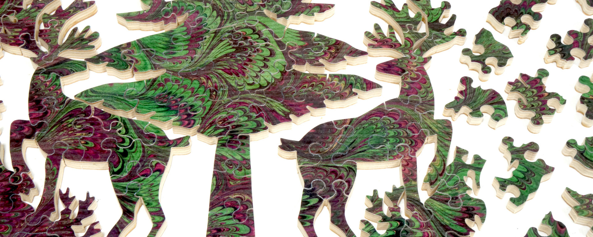 Wooden marbleized design puzzle showing an in progress green and maroon marble design of a tree and deer.