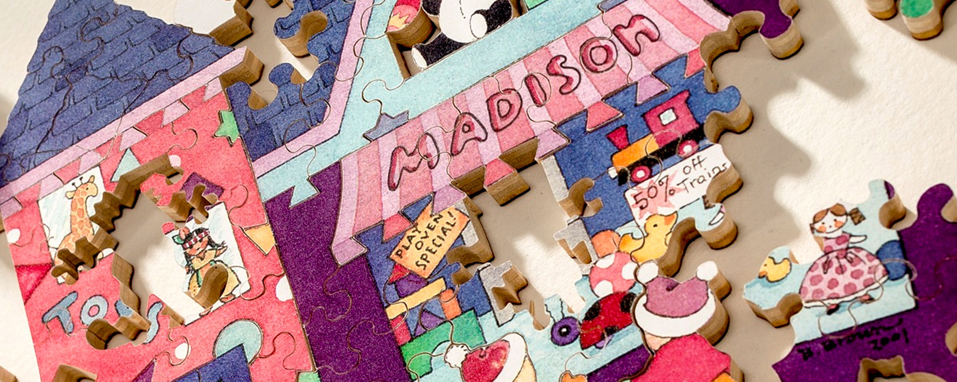 Wooden village puzzle in progress showing a brightly colored house with toy dolls and toy animals surrounding it.