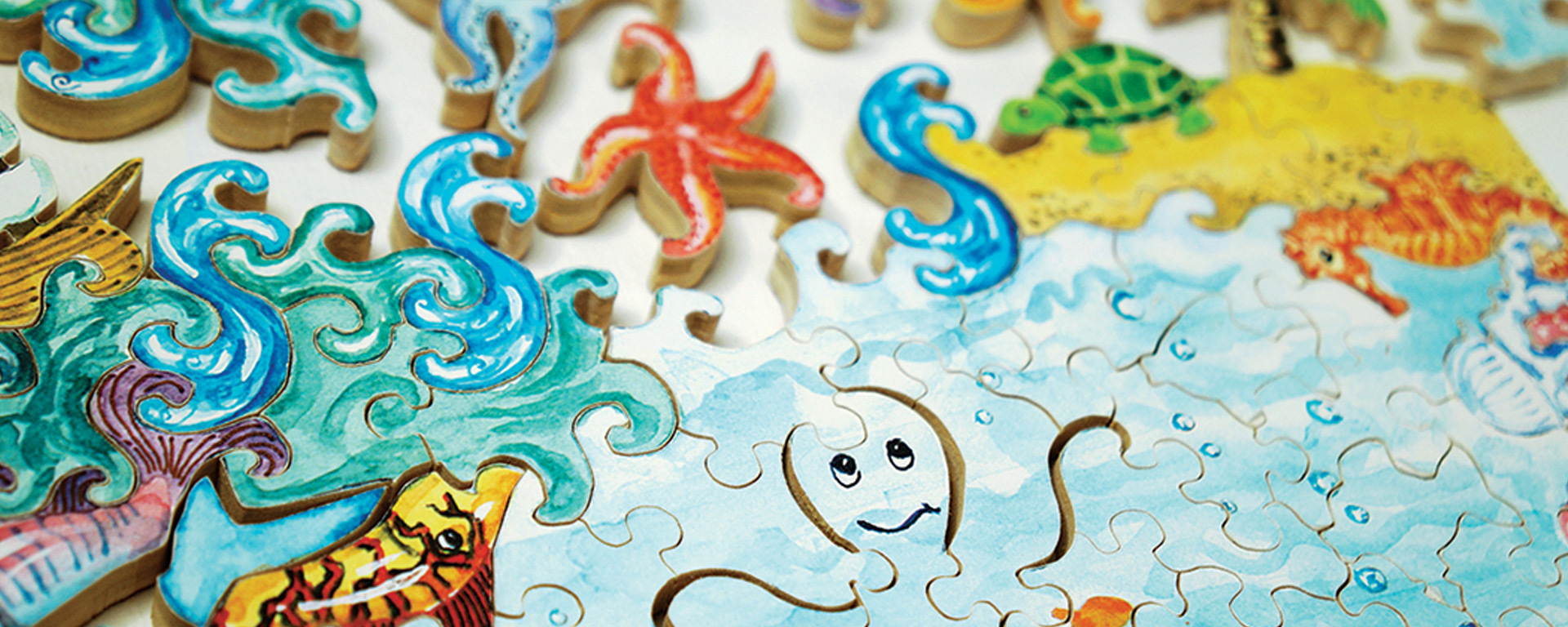 Wooden challenge puzzle in progress showing an oceanic scene of waves, starfish, turtles, seahorses, and an ocotopus.