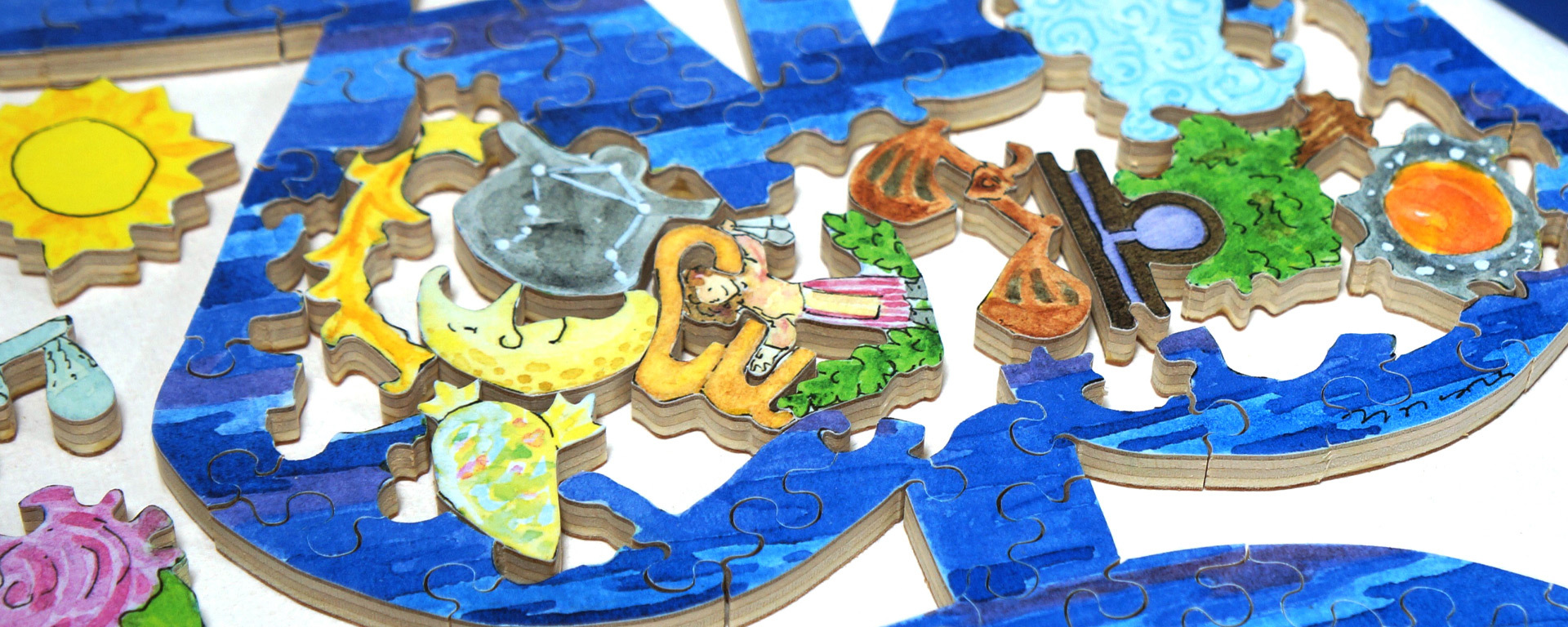 Wooden zodiac puzzle in progress featuring a blue outlined sign. Inside the sign are pieces that represent a sun, moon, rose, shooting star, and more.