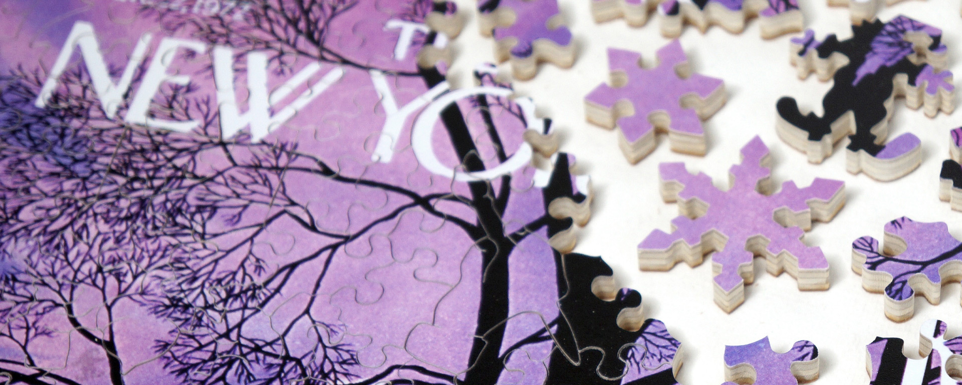 Wooden New Yorker cover art puzzle in progress featuring the silhouette of a tree with no leaves and a light purple sky in the background.