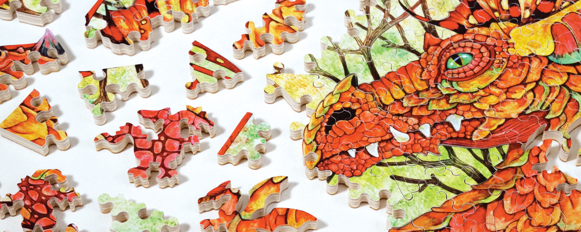 Wooden dinosaurs & dragons puzzle in progress featuring a big red dragon with green eyes.