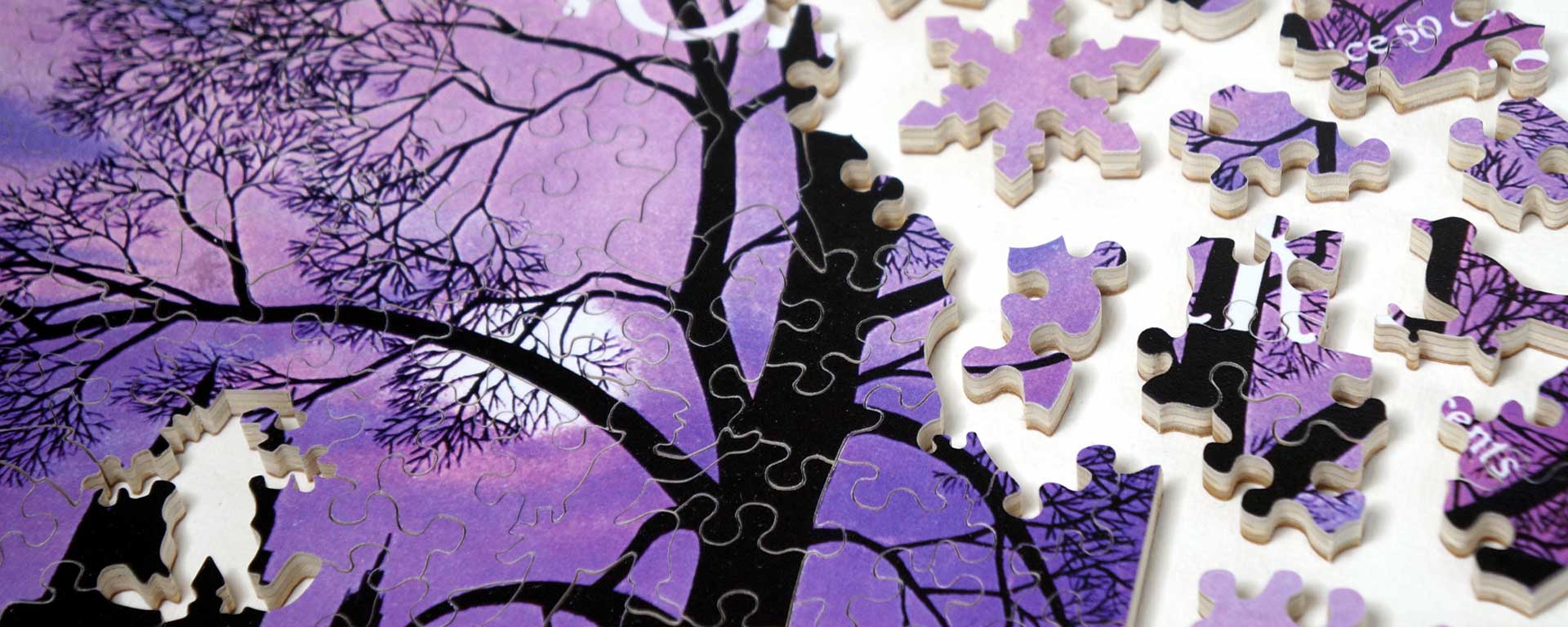 Wooden New Yorker cover art puzzle in progress featuring the silhouette of a tree with no leaves and a light purple sky in the background.