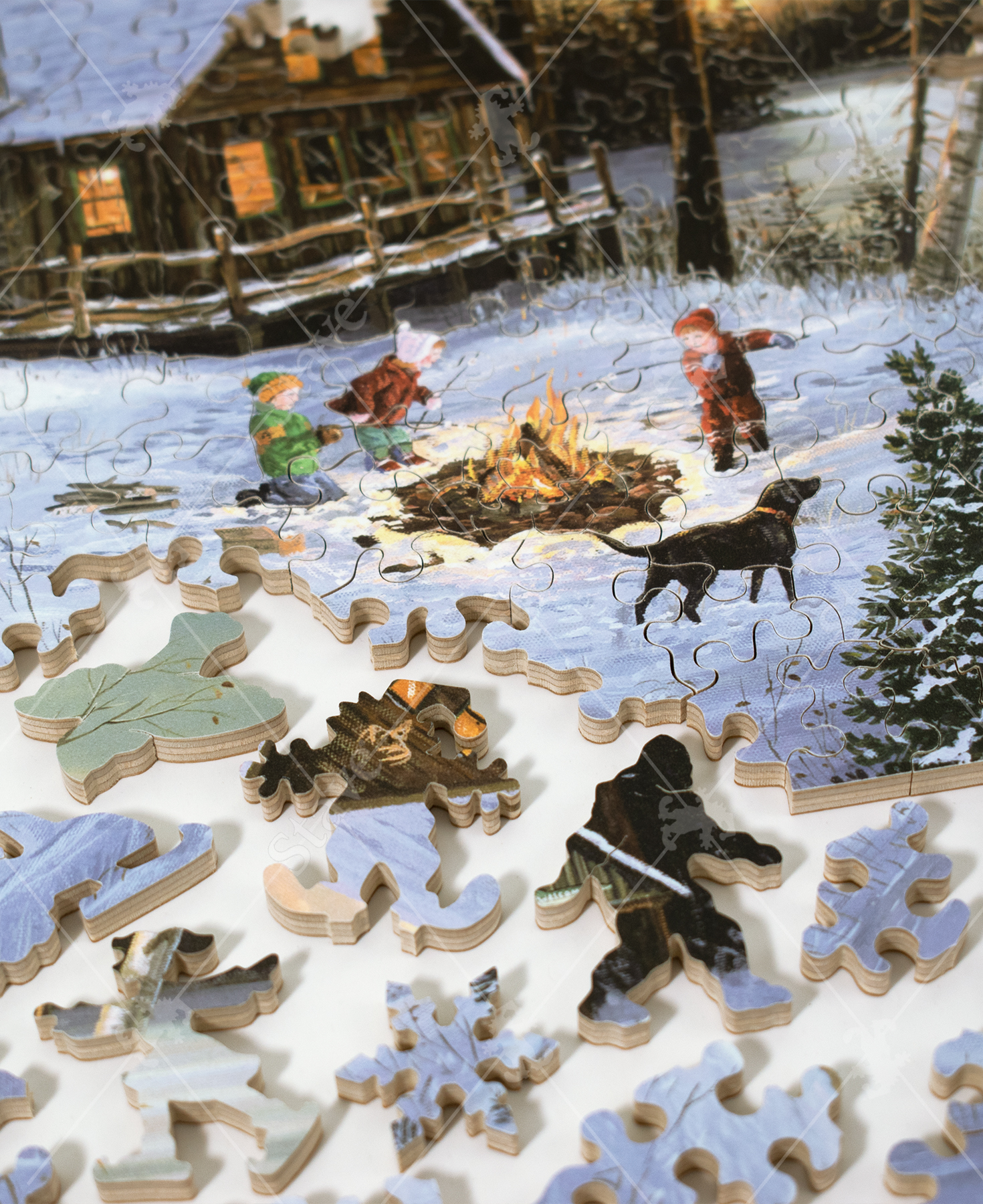 Taken apart puzzle pieces from Homeward Bound wooden jigsaw puzzle capturing a winter scene of a cabin in the woods by a frozen lake, where three children and their dog are roasting marshmallows by a campfire on a cold evening.