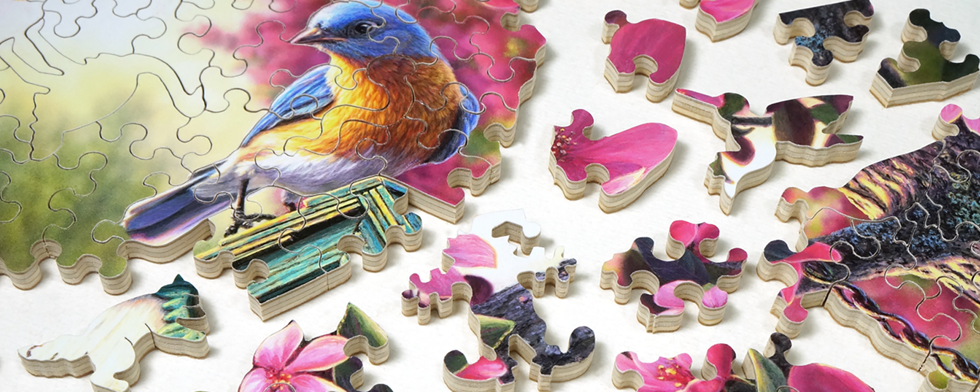 Wooden bird jigsaw puzzle in progress featuring a bluebird and a variety of whimsy shaped pieces such as a hummingbird and a fox.