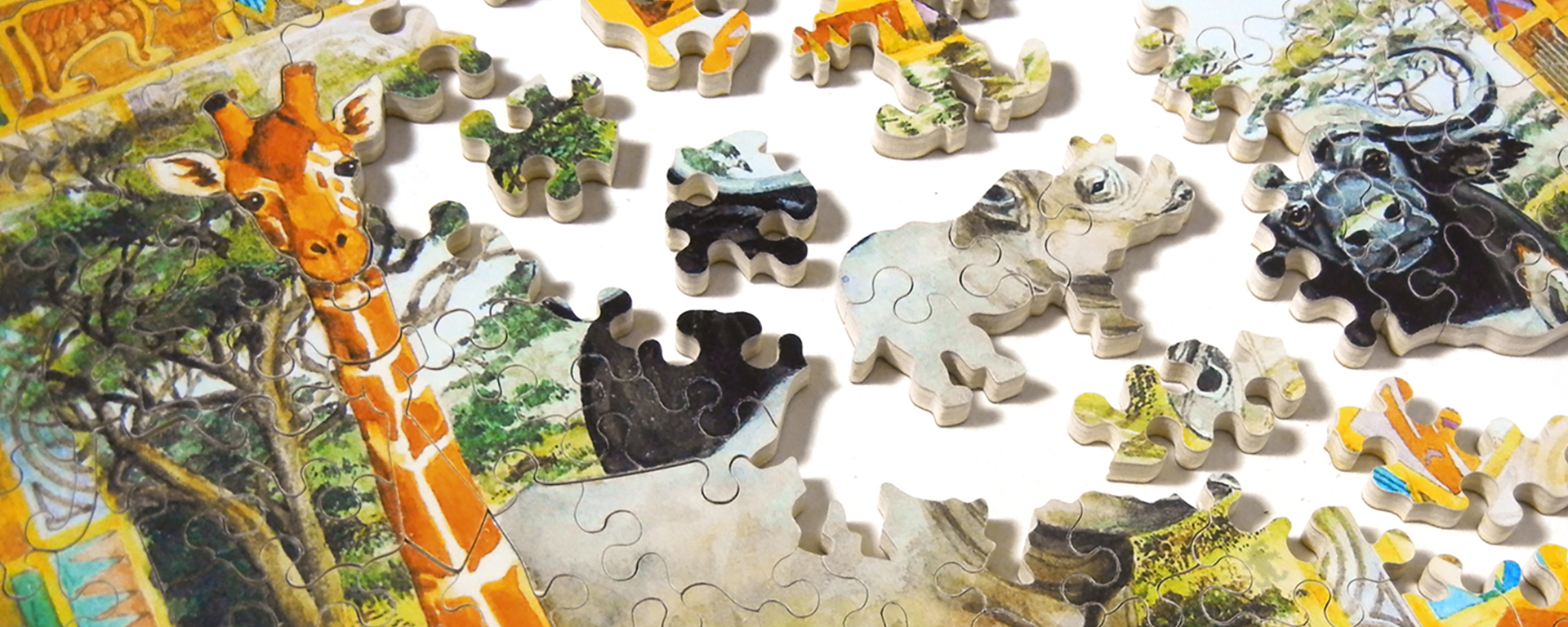 Wooden safari animal jigsaw puzzle in progress featuring a giraffe, rhino, musk ox, and other safari animals.