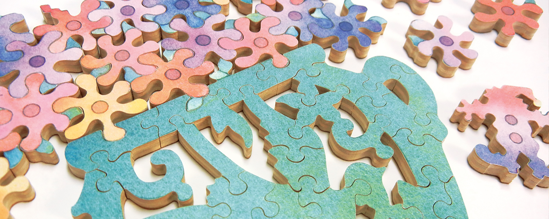 Wooden teaser bouquet jigsaw puzzle featuring a teal vase and a variety of different colored posies. The interior Teaser pieces nestle together, while still leaving some empty space between each piece.