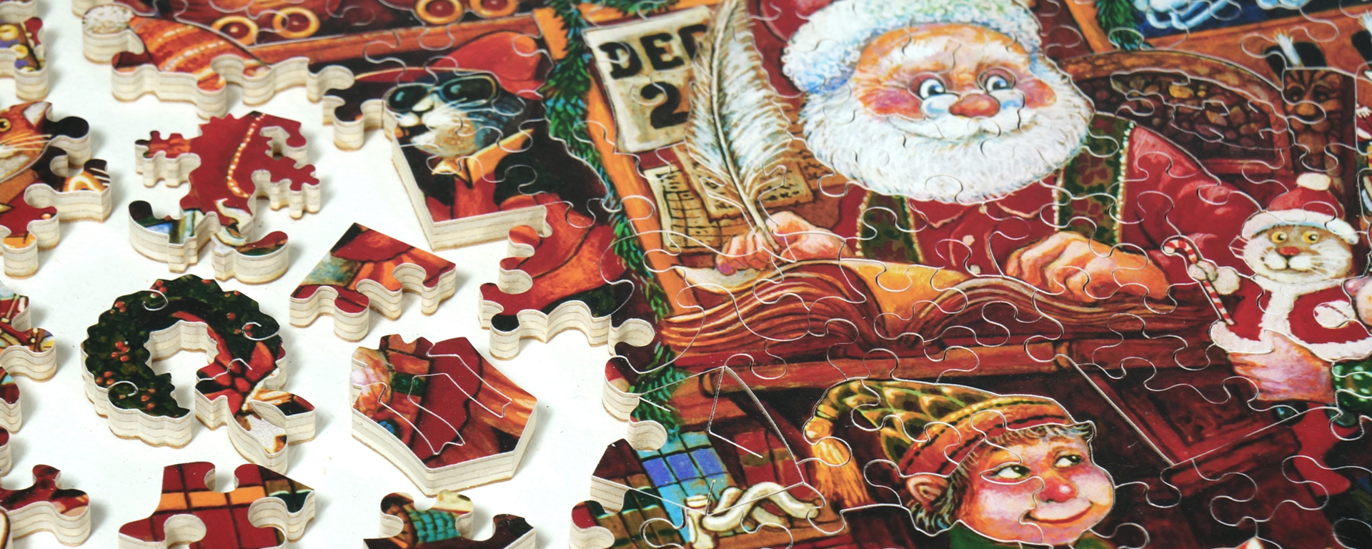Wooden jigsaw Santa puzzle portraying Santa Claus, his elf, and Christmas cats as well as puzzle pieces in classic Christmas shapes such as wreaths and presents.