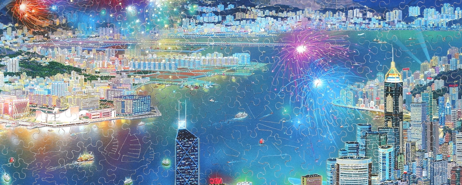 Wooden Asia puzzle featuring a celebration in Hong Kong. Fireworks light up the sky above a river with cityscape on either side.