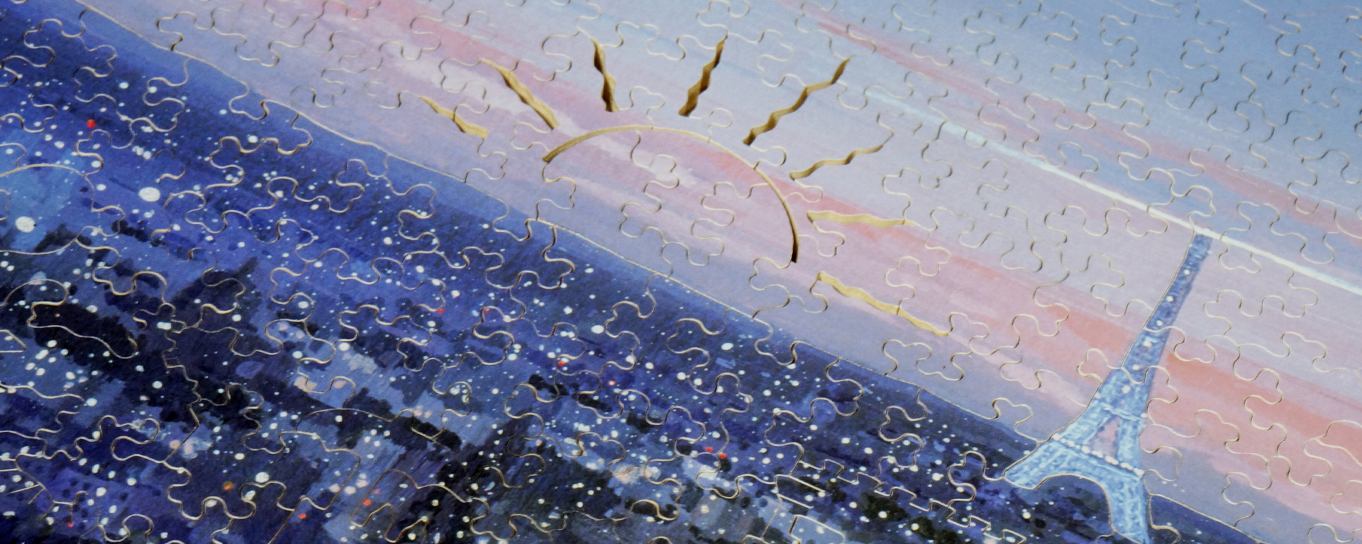 Wooden evening puzzle depicting a sunset over Paris with an outline of a sun cut out of the puzzles pieces and the eiffel tower in the background.
