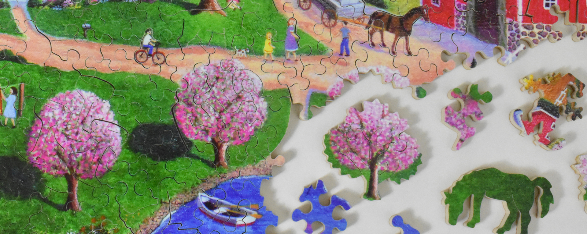 Wooden spring landscape puzzle in progress featuring pink flowering trees and whimsy shaped pieces such as a grazing horse and the Stave logo.