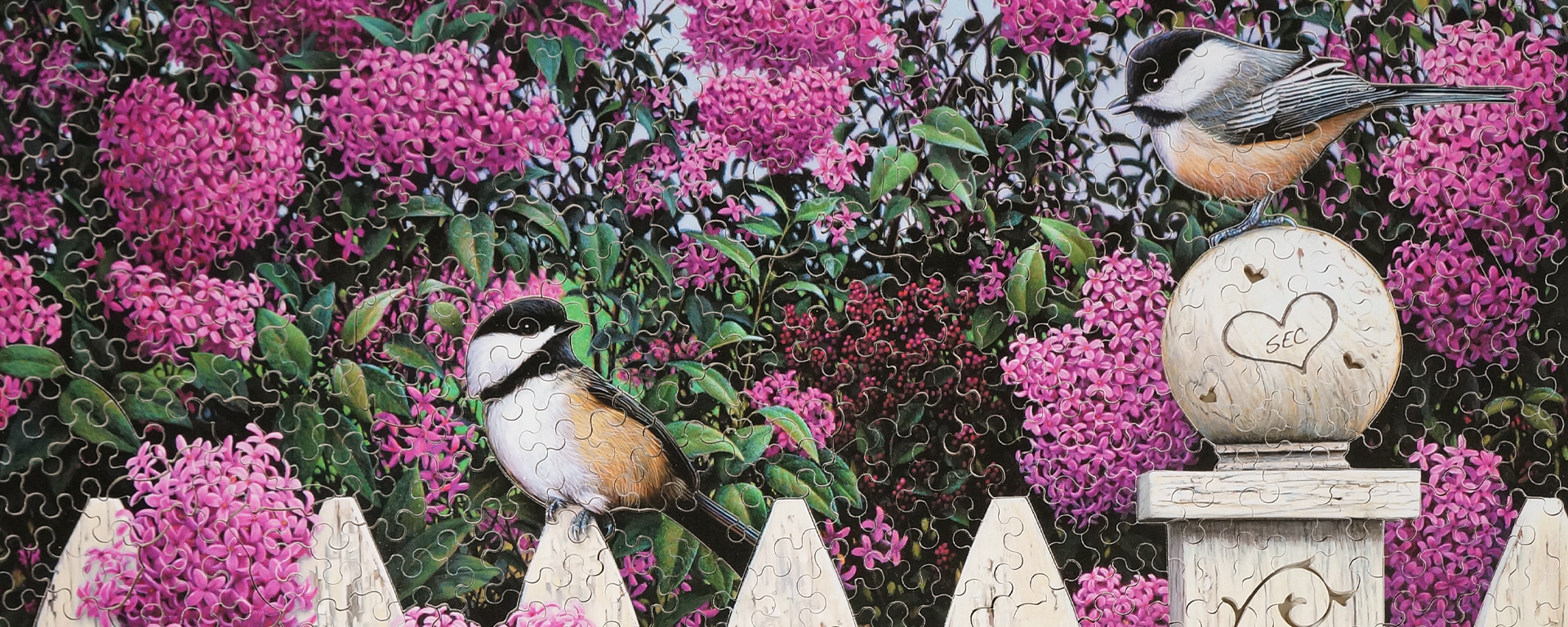 Wooden spring puzzle of Love Song by Kim Norlien with Chickadees perching on a wooden fence with lilacs in the background.