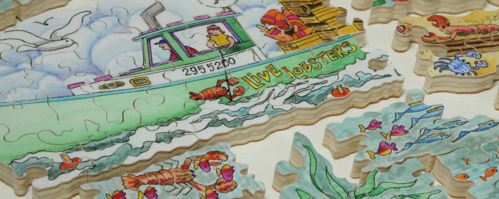 Wooden ocean puzzle in progress showing two indiviuals in a lobster boat catching lobsters while seagulls fly above and various colored fish and crabs surround the boat.