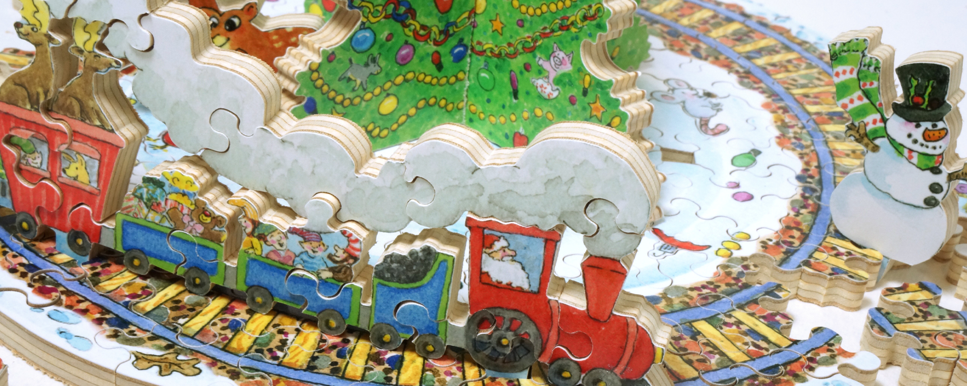 Wooden Santa's Village puzzle partially in progress showing Santa driving a train around a track with a decorated Christmas tree and reindeer inside it. Wood creatures and a snowman surround the train track.