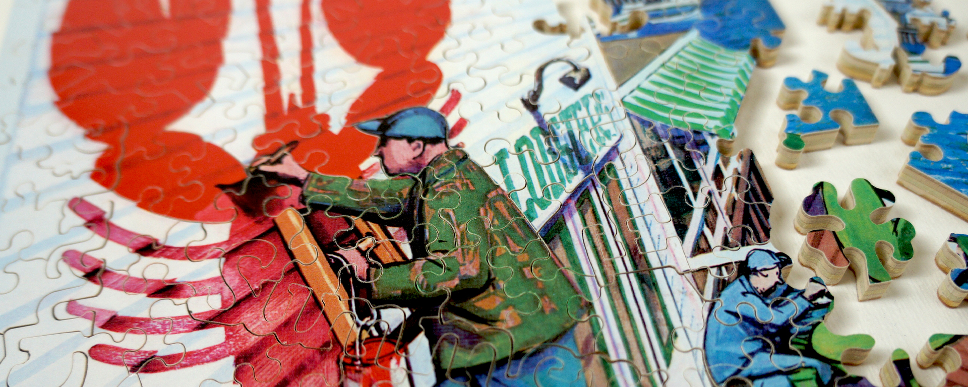 Wooden New Yorker cover art puzzle in progress featuring a man on a ladder painting a big red lobster on the exterior of a business.