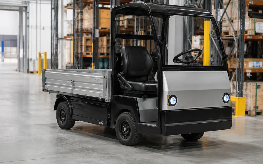 Compact industrial utility vehicle with cargo bed inside a warehouse