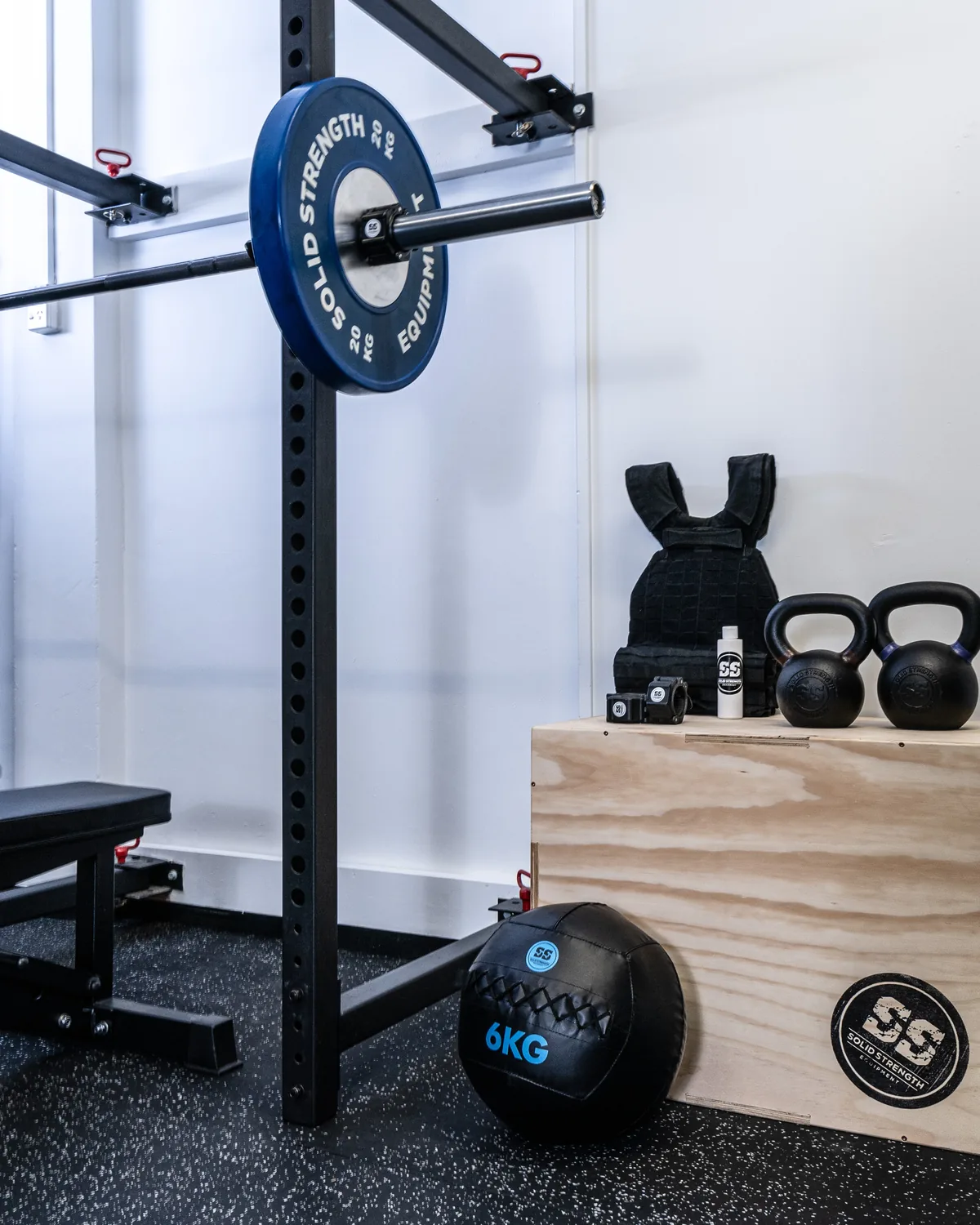 A Solid Strength rack loaded with bumper plates, with kettlebells and a plyo box