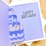 Inside of a handmade greeting card with cake on it and happy birthday sentiment on it.