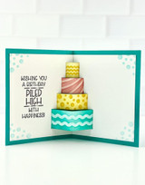 Inside of a handmade greeting card with cake in it and wishing you a birthday piled high with happiness sentiment on it.