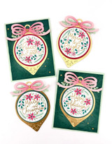 Four handmade greeting cards with various ornaments on each and different Christmas sentiments on each.