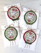 Four handmade greeting cards with various ornaments on each and different holiday sentiments on each.