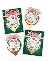 Four handmade greeting cards with ornaments on each and different holiday sentiments on each of them.