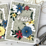 Handmade greeting card with flowers on it and thinking of you sentiment on it with crafting materials in background.