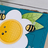 Up close of a handmade greeting card with a flower and two bumble bees on it.