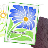 Handmade greeting card of a flower with so happy for you sentiment on it with papercrafting materials in background.