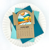 Handmade card with calendar with arched window and slates opening up to colorful rolling hills.