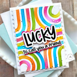 Handmade greeting card with colorful arches and lucky to call you a friend sentiment on it with cardstock in background.