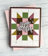 Handmade greeting card with patterned squares on it and happy birthday sentiment on it with cardstock in background.