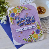 Up close of a handmade greeting card with flowers on it and thinking of you on your special day sentiment on it with flowers in the background.