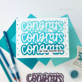Handmade greeting card with congrats on your amazing news sentiments on it with papercrafting materials in the background.