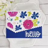 Handmade greeting card with flowers on it and hello sentiment on it with flowers in the background.