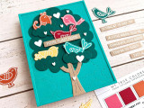 Handmade greeting card with doodle birds in tree with home tweet home sentiment with crafting supplies in background.