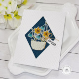 Handmade greeting card with hello sentiment made with diamond shapes and flowers with flowers in background.