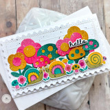 Handmade greeting card with mushrooms, flowers, and snails with hello sentiment with cardstock in the background.