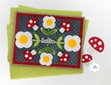 Handmade greeting card with mushrooms and flowers on it with hello sentiment and cardstock in background.