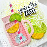 Handmade greeting card with a drink cup, citrus fruit, and you're the zest sentiment on it with cardstock in the background.