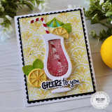 Handmade greeting card with a drink cup, citrus fruit, and cheers to you sentiment on it with flowers in the background.