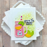 Handmade greeting card with a drink cup, citrus fruit, and you're the zest sentiment on it with cardstock in the background.