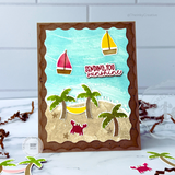 Handmade greeting card with beach theme including a crab, palm trees, and sailboat with sending you sunshine sentiment on it with paper crafting supplies in background.