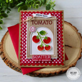 Handmade greeting card with tomatoes on it and scatter seeds of kindness sentiment on it with cardstock and a plant in the background.