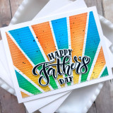 Handmade greeting card with colorful rays and happy father's day sentiment on it with cardstock in background.
